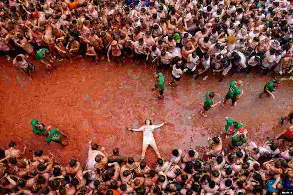 Un participante yace sobre pulpa de tomate, mientras la gente asiste al festival anual de lucha contra la comida 'La Tomatina' en Buñol.