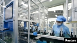 资料照片:中国广东东莞一家生产电动汽车锂离子电池的工厂工人在生产线上。（2022年10月16日）
