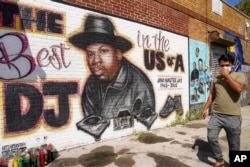FILE - A pedestrian passes a mural of rap pioneer Jam Master Jay of Run-DMC, by artist Art1Airbrush, Aug. 18, 2020, in the Queens borough of New York. (AP Photo/John Minchillo, File)