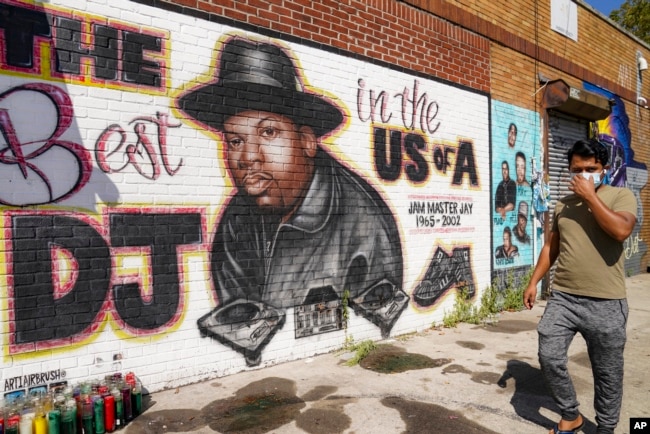 FILE - A pedestrian passes a mural of rap pioneer Jam Master Jay of Run-DMC, by artist Art1Airbrush, Aug. 18, 2020, in the Queens borough of New York. (AP Photo/John Minchillo, File)