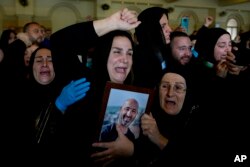 Manal Jaafar reacts as she holds a photo of her husband Rabih al-Maamari, a cameraman for Lebanese broadcaster Al-Mayadeen who, along with correspondent Farah Omar, was killed by an Israeli strike, during his funeral in Beirut, Nov. 22, 2023.