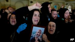 2023年11月22日在贝鲁特举行的葬礼上，马纳尔·贾法尔(Manal Jaafar)拿着丈夫拉比·马马里(Rabih al-Maamari)的照片声泪俱下。拉比·马马里(Rabih al-Maamari)是黎巴嫩广播公司艾勒-麦亚丁(Al-Mayadeen)的摄影师，他与记者法拉·奥马尔一起在以色列的袭击中丧生 。 （美联社图片）