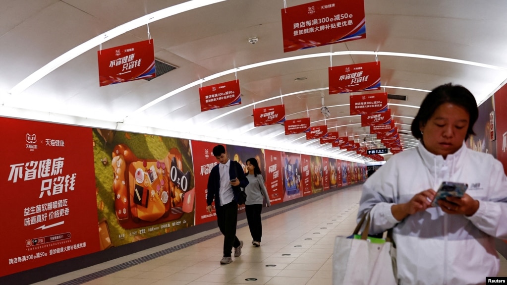 北京地铁乘客走过阿里巴巴为11月11日光棍节大促销所作广告的通道。（2023年10月26日）(photo:VOA)