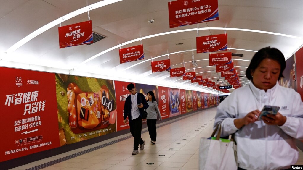 北京地铁乘客走过阿里巴巴为11月11日光棍节大促销所作广告的通道。（2023年10月26日）(photo:VOA)