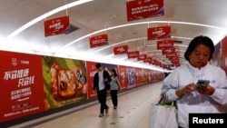 北京地铁乘客走过阿里巴巴为11月11日光棍节大促销所作广告的通道。（2023年10月26日）