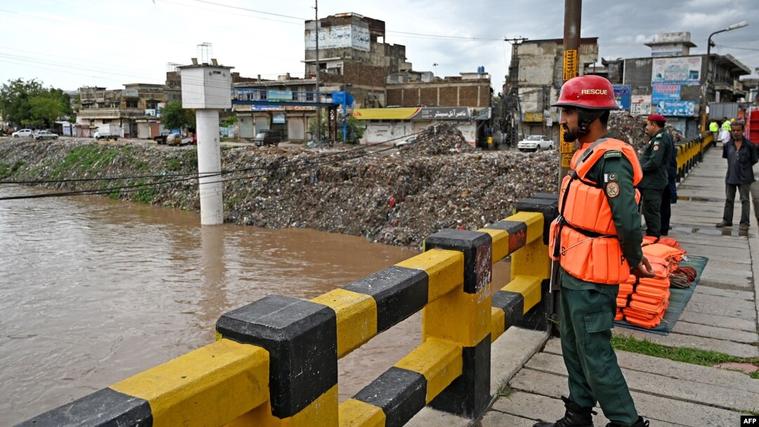 Rescue workers monitor the flood situation at a bridge over a stream in Rawalpindi, Pakistan, on July 7, 2023. 