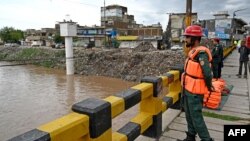 Rescue workers monitor the flood situation at a bridge over a stream in Rawalpindi, Pakistan, on July 7, 2023. 