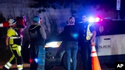 Neighborhood residents speak to Austin Police officers in Austin, Texas late Dec. 5, 2023. Texas authorities say a daylong series of attacks in Austin has left four people dead and at least three injured. (Sara Diggins /Austin American-Statesman via AP) 