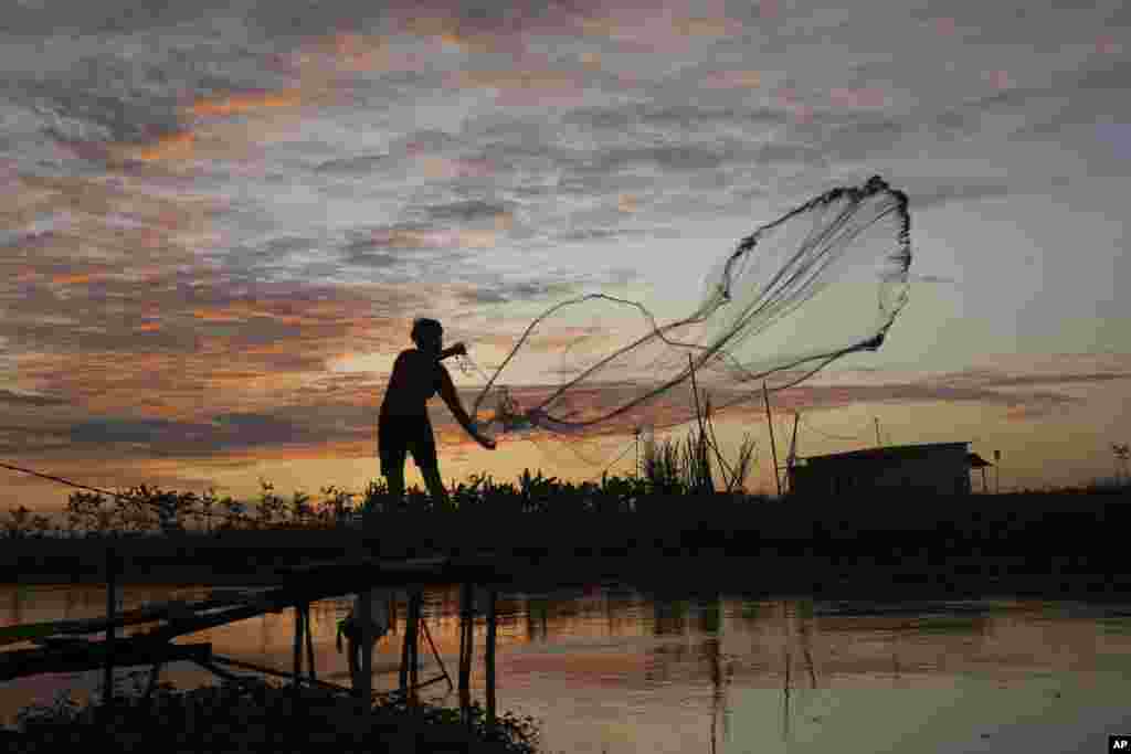 A local villager casts his net into a canal in Tuol village outside Phnom Penh, Cambodia.