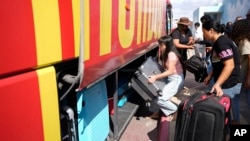 People load their belongings onto a bus as they evacuate from the southern Israeli town of Sderot, Oct. 15, 2023.