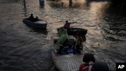 Spasioci vuku čamce sa stanovnicima za vreme evakuaicje iz poplavljenih delova Hersona, 6. juna 2023. (Foto:AP/Felipe Dana)