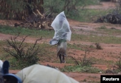 A Sudanese boy who fled the conflict in Sudan's Darfur region, uses a plastic bag to cover himself from the rain during a storm at a refugee camp in Ourang on the outskirts of Adre, Chad, July 30, 2023.