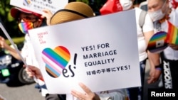 FILE— A participant holds a sign as they march during the Tokyo Rainbow Pride parade, celebrating advances in LGBTQ rights and calling for marriage equality, in Tokyo, Japan April 23, 2023. 