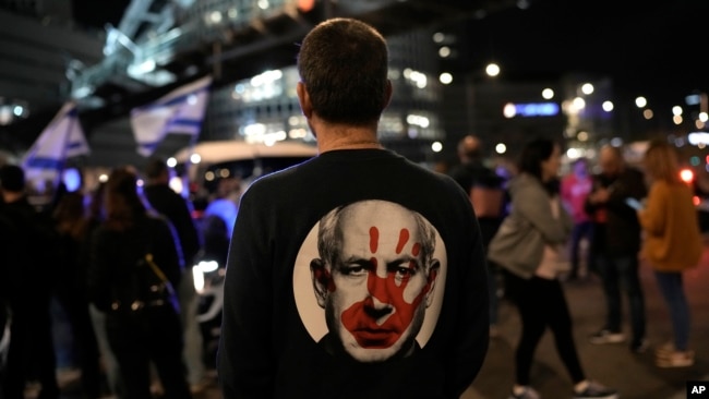 A protester, wearing a shirt with an image of Israeli Prime Minister Benjamin Netanyahu covered with a bloody hand print - stands at a rally in Tel Aviv, Israel, Jan. 20, 2024, demanding the release of hostages kidnapped on Oct. 7 by Hamas militants.