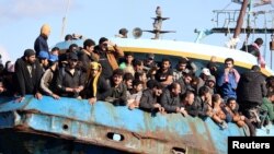 Migran berdiri di atas kapal penangkap ikan di Pelabuhan Paleochora, setelah operasi penyelamatan di lepas pantai Pulau Kreta, Yunani, 22 November 2022. (Foto: Reuters)