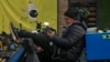 FILE - A man sits on his bike watching video from a social media app via his smartphone on a street in Beijing, Feb. 27, 2023. 