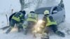 En esta fotografía proporcionada por el Servicio de Emergencia de Ucrania, trabajadores de emergencia de Ucrania intentan empujar un automóvil atrapado en la nieve en la carretera de la región de Odesa, Ucrania, el lunes 27 de noviembre de 2023.