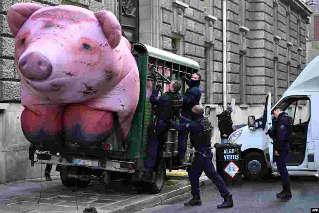 French police officers attempt to dismantle a giant inflatable pig in a trailer blockading a street by Greenpeace activists taking part a demonstration against agricultural policies and denouncing the ecological impact of industrialized farming, near the Ministry of Agriculture in Paris.