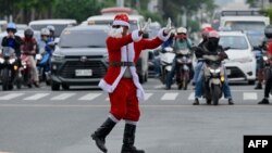 Petugas lalu lintas Ramiro Hinojas, berpakaian Sinterklas saat perayaan, mengarahkan kendaraan di sepanjang Macapagal Avenue di Pasay, Metro Manila, 28 November 2023. (JAM STA ROSA / AFP)