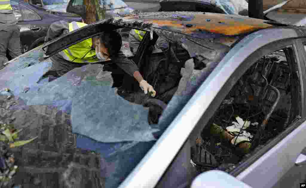 A Hezbollah Civil defense worker searches for body remains inside a burned car, near an apartment building where an apparent Israeli strike Tuesday killed top Hamas political leader Saleh Arouri, in the southern suburb of Beirut that is a Hezbollah stronghold, Lebanon.