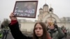 Seorang perempuan memegang potret Alexey Navalny dan istrinya, Yulia, di luar gereja tempat pemakamannya berlangsung, di Moskow, Rusia, 1 Maret 024. (Foto: AP Photo)