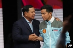 Calon presiden Prabowo Subianto, kiri, berjabat tangan dengan pasangannya Gibran Rakabuming Raka, putra sulung Presiden Joko Widodo, di akhir debat calon wakil presiden yang disiarkan televisi di Jakarta, 21 Januari 2024. (Foto: AP )