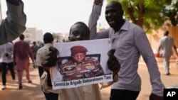 Des Nigériens participent à une marche appelée par des partisans du chef du coup d'État, le général Abdourahmane Tchiani, photographié, à Niamey, au Niger, le 30 juillet 2023.