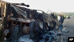 People look at a burnt vehicle which was torched by gunmen after they killed passengers on a highway in Musakhail, a district in Baluchistan province in restive southwestern Pakistan, Aug. 26, 2024.