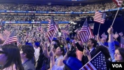 Asistentes a la Convención Nacional Demócrata 2024 ondean banderas de EEUU en el United Center de Chicago, el 22 de agosto de 2024. 