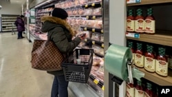 A woman studies a package of meat at a Whole Foods grocery store, Jan. 19, 2024, in New York.