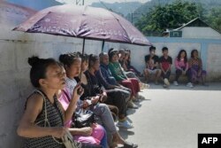 Warga setempat menunggu di luar TPS untuk memberikan suara mereka pada pemilihan dewan negara bagian di Aizawl pada 7 November 2023. (Biju BORO / AFP)