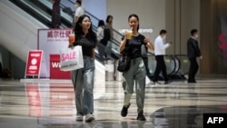 FILE - People walk in a shopping mall in Beijing on June 15, 2023. 