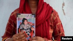 FILE - Poli Devi, whose 11-month-old daughter Janvi was among the children who died due to kidney injury after consuming contaminated cough syrup, holds a photo of her at their house in Ramnagar on the outskirts of Jammu, India, March 28, 2023.