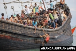 Pengungsi Rohingya yang baru tiba terdampar di perahu karena masyarakat sekitar memutuskan untuk tidak mengizinkan mereka mendarat setelah memberikan air dan makanan di Pineung, Aceh, 16 November 2023. (Foto: AMANDA JUFRIAN/AFP)