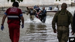 Emergency teams help rush to safety injured civilians who had allegedly came under fire from Russian forces while trying to evacuate by boat from the Russian-occupied east bank of a flooded Dnipro River to Ukrainian-held parts of Kherson, June 11, 2023.
