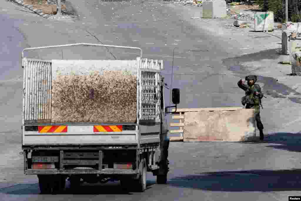 An Israeli soldier stands guard on a blocked road as the entrance to Hebron is closed, in the Israeli-occupied West Bank, Oct. 8, 2023. 