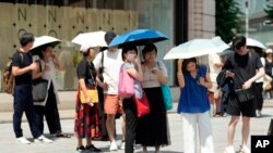 Sejumlah warga memakai payung untuk melindungi mereka dari sengatan matahari saat berjalan di Tokyo, pada 8 Juli 2024. (Foto: AP/Eugene Hoshiko)