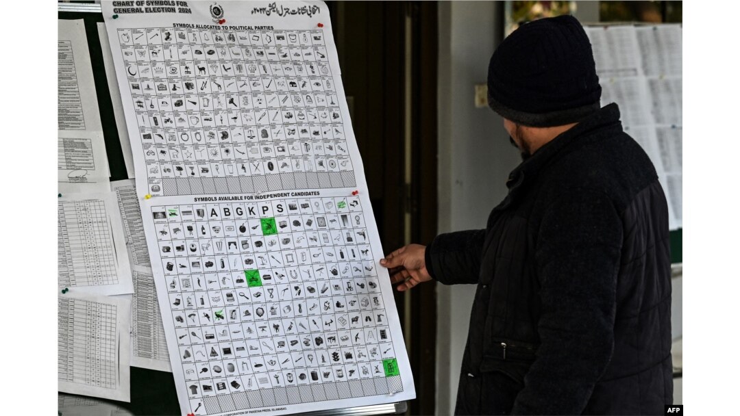 Seorang pria melihat grafik yang berisi simbol partai politik dan kandidat independen di kantor pemilu di Rawalpindi, 15 Januari 2024 menjelang pemilu Pakistan.(Aamir QURESHI / AFP)