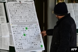 Seorang pria melihat grafik yang berisi simbol partai politik dan kandidat independen di kantor pemilu di Rawalpindi, 15 Januari 2024 menjelang pemilu Pakistan.(Aamir QURESHI / AFP)