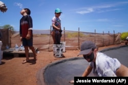 From left, siblings Kekanemekala, Pi'ilani and Anali'a Taniguchi Butler use wet clay to make salt bedson July 12, 2023, in Hanapepe, Hawai. (AP Photo/Jessie Wardarski)