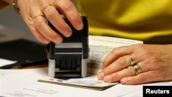 Un employé valide une extension de visa sur le passeport d'un étudiant étranger dans un bureau des visas étrangers à Paris, le 18 novembre 2011.