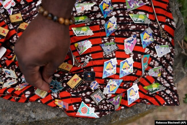 Seorang pejalan kaki memilih pin umilik Thurston Bilal dari Los Angeles di Olimpiade Musim Panas 2024, Selasa, 23 Juli 2024, di Paris, Prancis. (Foto: AP/Rebecca Blackwell)