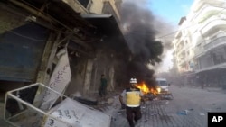 In this photo provided by the Syrian Civil Defense White Helmets, a Syrian White Helmet civil defense worker runs at the site where a shell struck in the outskirts of the northern town of Jisr al-Shoughour, west of the city of Idlib, Syria, Oct. 5, 2023. 