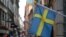 Bendera Swedia berkibar di luar sebuah toko dengan latar belakang kota tua Stockholm, Swedia, 14 Juli 2023. (Foto: REUTERS/Tom Little)