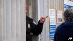 A United States Customs and Border Protection officer points towards a line of people waiting to apply for asylum at the pedestrian entrance to the San Isidro Port of Entry, linking Tijuana, Mexico with San Diego, June 1, 2023, in Tijuana, Mexico. 