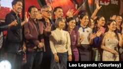 ບັນດາສິລະປິນນັກຮ້ອງແລະນັກສະແດງຊັ້ນນຳຂອງລາວ ພາກັນໂບກມືທັກທາຍຜູ້ຊົມຫຼັງຈາກສິ້ນສຸດການສະແດງ ໂດຍມີຍານາງສະເພດ ຈຸນລະມະນີ ຜູ້ສະໜັບສະໜຸນ ງານການສະແດງທີ່ເອີ້ນວ່າ Lao Legends ຢືນຢູ່ກາງ.