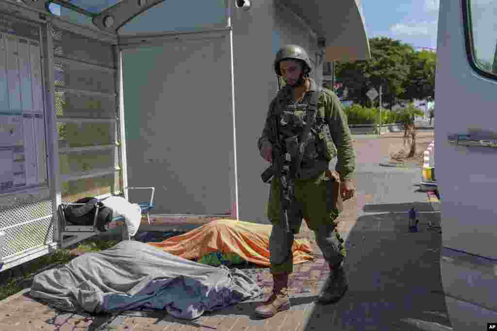 An Israeli soldier stands by the bodies of Israelis killed by Palestinian armed militants who entered from the Gaza strip, in the southern Israeli city of Sderot, Oct. 7, 2023.