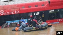 South Korean rescue workers search for missing persons near a bus along a deluged road leading to an underground tunnel where some 15 cars were trapped in flood waters after heavy rains in Cheongju, July 16, 2023. 