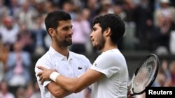 Spain's Carlos Alcaraz acknowledges Serbia's Novak Djokovic after winning the final Wimbledon math, July 16, 2023.