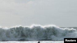 A surfer tries to navigate through a rough sea during Storm Ciaran, in Tramore, Ireland. REUTERS/Clodagh Kilcoyne
